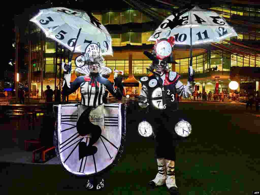 Australian performers illuminated with real clocks titled &#39;The Time Minder&#39; attend a media preview of the Night Festival in Singapore.