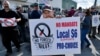 Alec Young, a shipfitter at Bath Iron Works, center, demonstrates against COVID-19 vaccine mandates outside the shipyard, Oct. 22, 2021, in Bath, Maine.
