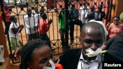 Employees of the Daily Monitor newspaper with their mouths taped shut, sing slogans during a protest against the closure of their premises by the Uganda government, outside their offices in the capital Kampala, Uganda, May 20, 2013.