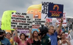Protestors hold up anti President Donald Trump signs during a rally, June 18, 2019, in Orlando, Fla.