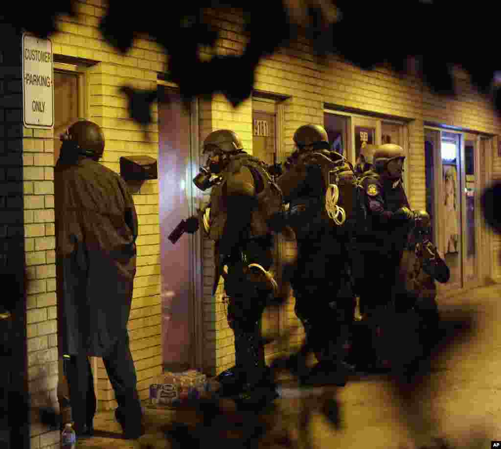 Huquq-tartibot xodimlari binoni tekshiruvdan o'tkazmoqda, Ferguson, 17-avgust, 2014-yil.