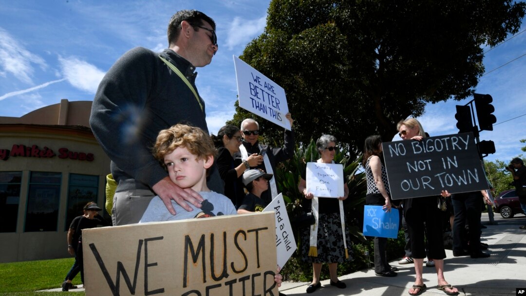 FILE - This April 28, 2019, file photo shows Kyle Fox holding a sign with his father Brady Fox in support of the victims of Chabad of Poway synagogue shooting in Poway, Calif. 