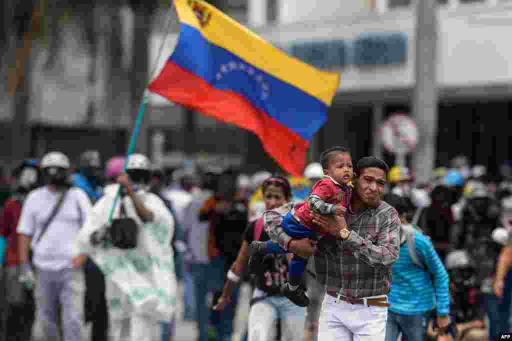 People flee during a clash between opposition demonstrators and riot police in a protest against the government of President Nicolas Maduro in Caracas, Venezuela.