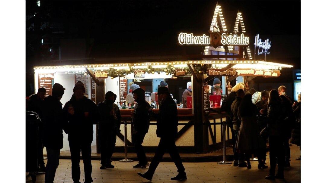 People stand around a mulled wine to-go stand at a Christmas market at Breitscheidplatz square, amid the COVID-19 pandemic in Berlin, Germany, Dec.10, 2020.