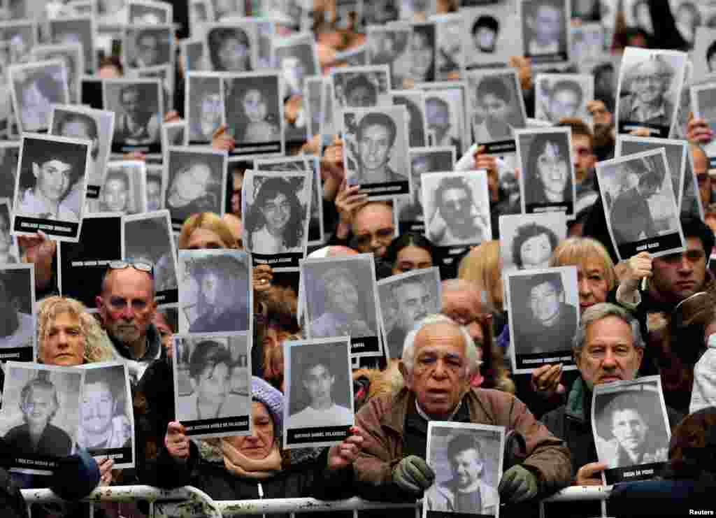 People hold up portraits of the victims of the 1994 bombing of the Argentine Israeli Mutual Association (AMIA) community center as they gather to commemorate those killed, on the 24th anniversary of the attack in Buenos Aires, Argentina, July 18, 2018.