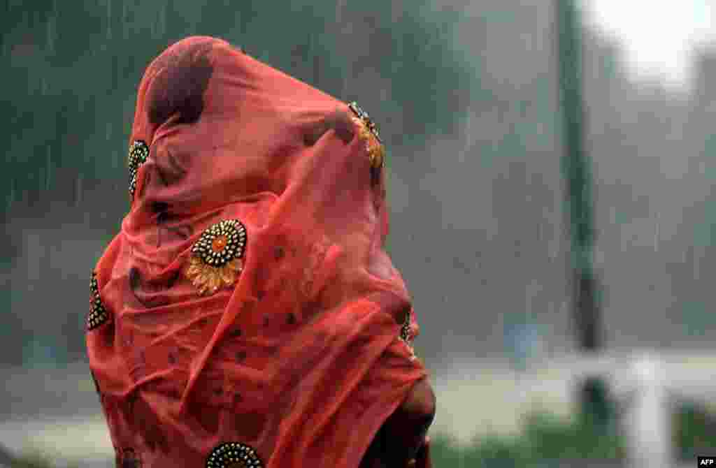 An Indian woman covers her baby under her saree during heavy rain at Rajpath in New Delhi.
