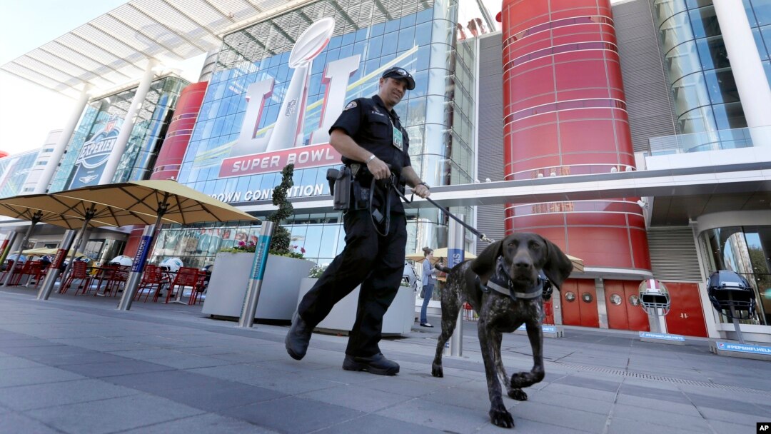 Officer Keith McCart, of the Long Beach, California, Police Department, patrols with K-9 Pidura outside the George R. Brown Convention Center, location of the Super Bowl 51 media center, Jan. 31, 2017, in Houston.