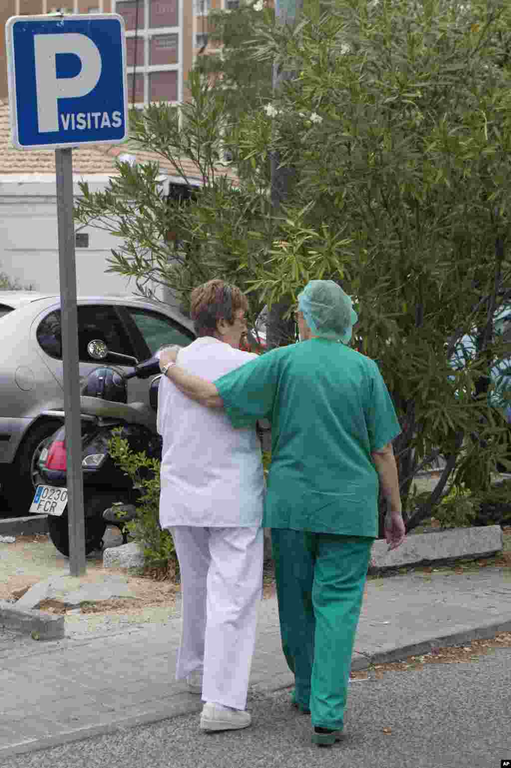 Hospital staff members walk back into the Carlos III Hospital where a Spanish nurse, believed to have contracted the Ebola virus from a 69-year-old Spanish priest, is being treated, in Madrid, Spain, Oct. 7, 2014.