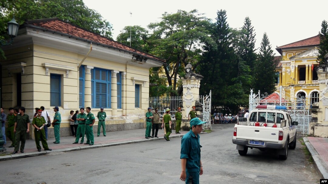 FILE - Policemen and security staff stand outside the main entrance gate of Ho Chi Minh City's People's Court where three bloggers stand trial for 'anti-state propaganda'.