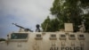 A Ugandan police officer serving with the African Union Mission in Somalia's first Formed Police Unit stands at the top of an armored personnel carrier at a police station in the capital Mogadishu, August 7, 2012.