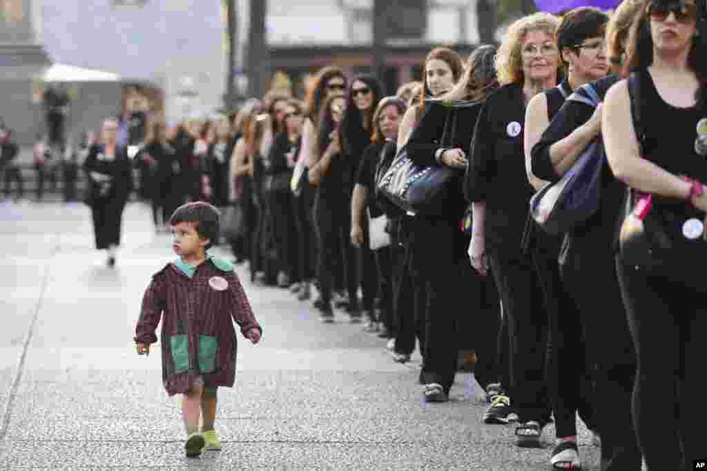 A boy looks to people dressed in black as they demonstrate at a parade during the International Day for the Elimination of Violence against Women in Montevideo, Uruguay, Nov. 25, 2016.