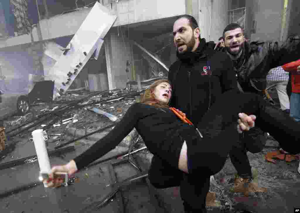 A man carries an injured woman away from the site of a car bomb explosion in a southern suburb of Beirut, Jan. 2, 2014.