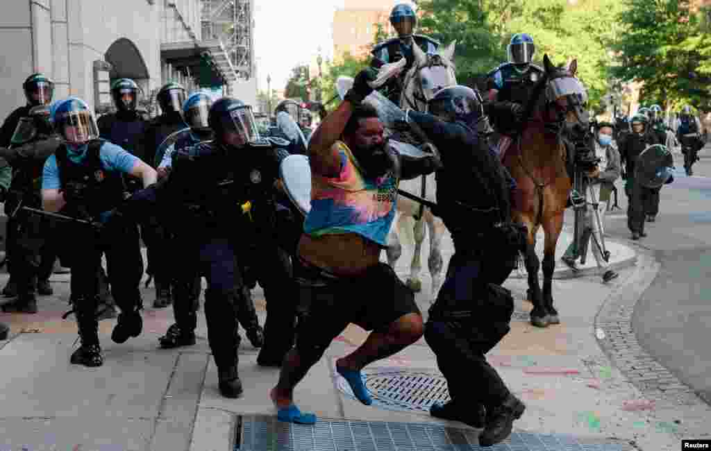 Riot police chase a man as they rush protesters to clear Lafayette Park and the area around it across from the White House for President Donald Trump to be able to walk through for a photo opportunity in front of St. John's Episcopal Church, June 1, 2020.