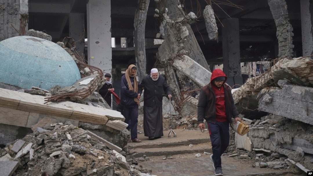 ARCHIVO - Un grupo de palestinos camina cerca de las ruinas de una mezquita afectada por ataques aéreos en la ciudad de Gaza, el 7 de marzo de 2025. Un grupo de expertos busca documentar denuncias de crímenes de lesa humanidad en la región. 