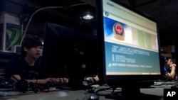 一位电脑用户坐在网吧里，他旁边的屏幕上显示着中国公安发布的互联网合理使用规定。