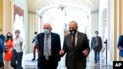 Sen. Bernie Sanders, I-Vt., left, and Senate Majority Leader Chuck Schumer of N.Y., right, speak to members of the media as they walk out of a budget resolution meeting at the Capitol in Washington, Aug. 9, 2021. 