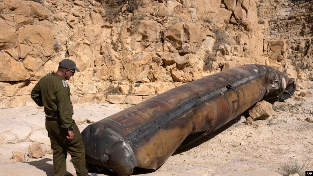 A member of the Israeli military personnel examines a part of an Iranian ballistic missile, recently located in an open area near the southern city of Arad, on April 24, 2024.