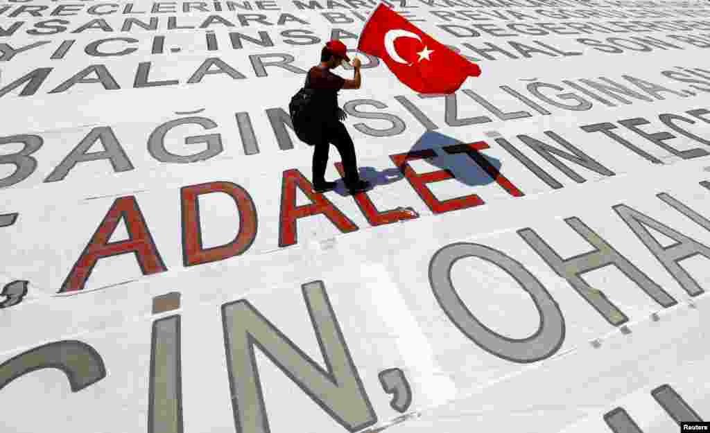 A young man walks with a Turkish national flag on a huge banner during a rally to mark the end of the main opposition Republican People's Party (CHP) leader Kemal Kilicdaroglu's 25-day-long protest, dubbed "Justice March", against the detention of the party's lawmaker Enis Berberoglu, in Istanbul, July 9, 2017