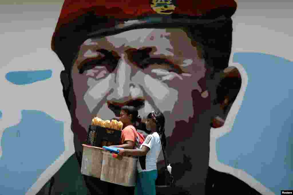 Women walk past a portrait of Venezuela&#39;s late President Hugo Chavez in Caracas, Aug. 7, 2017.