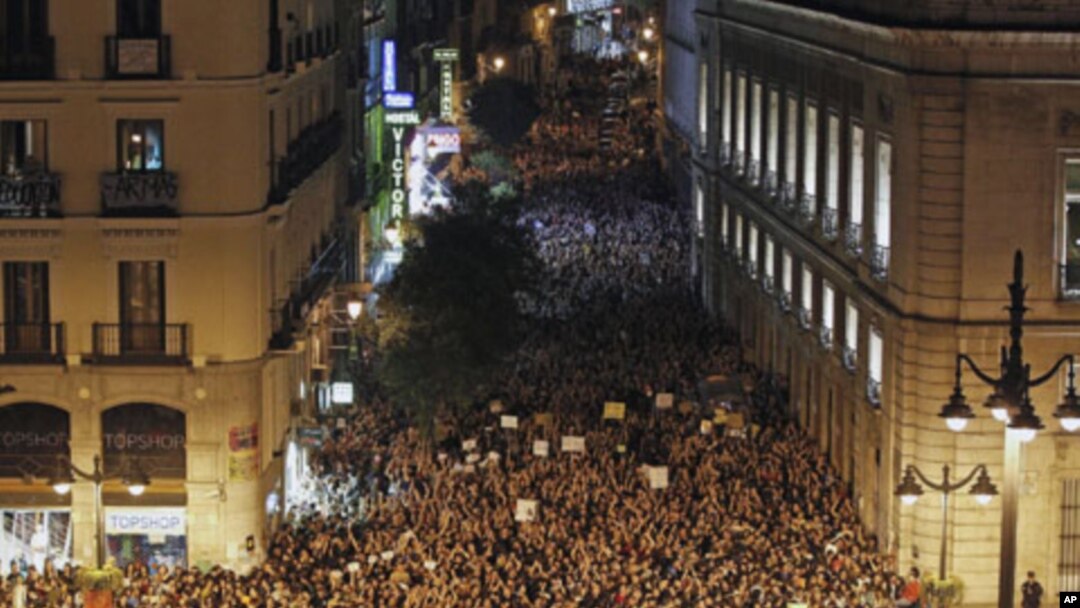 Demonstrators raise their arms just after midnight as they fill up Madrid's Puerta del Sol, spilling into sidestreets, early May 21, 2011