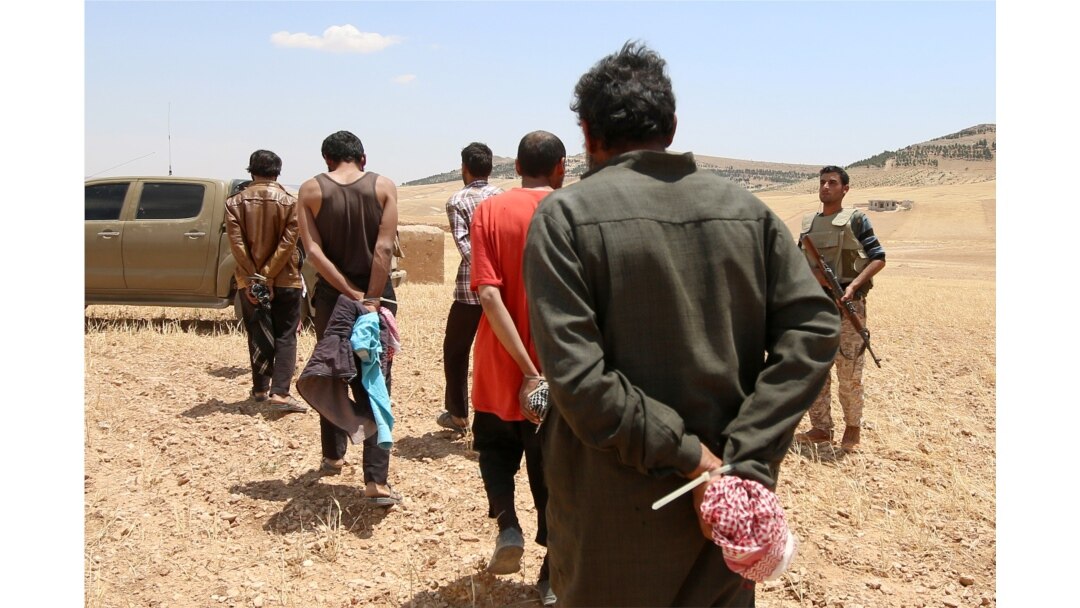 FILE - Men who Syrian Democratic Forces fighters claimed were Islamic State fighters walk as they are taken prisoner after the SDF advanced in the southern rural area of Manbij, in Aleppo Governorate, Syria, May 31, 2016.