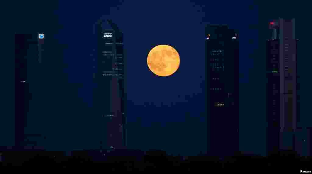 The full moon rises between buildings in the Four Towers business district in Madrid, Spain, July 9, 2017.