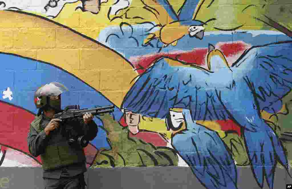A National Guard points his weapon during clashes with anti-government demonstrations in the streets of Caracas, Venezuela.