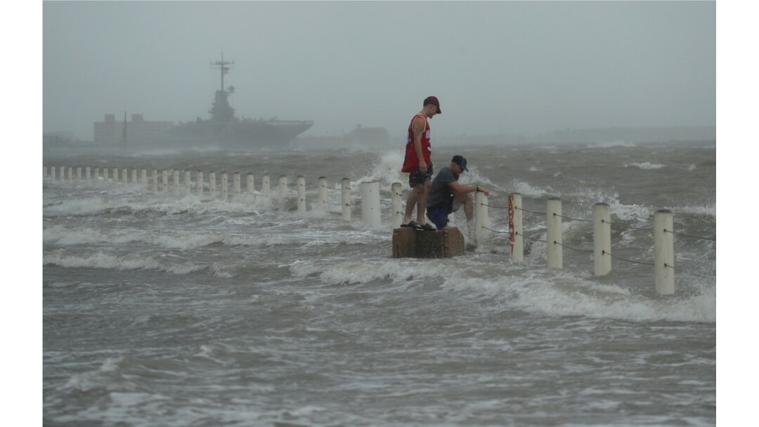 Two men stand near a seawall as Hurricane Hanna makes landfall, July 25, 2020, in Corpus Christi, Texas.