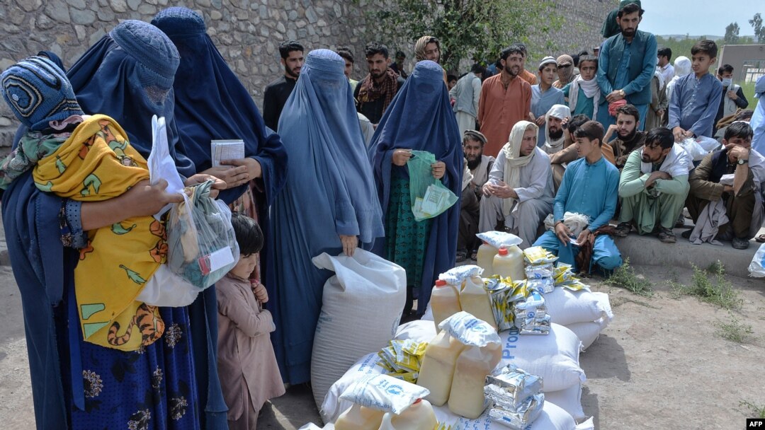 FILE - Afghan women receive food donations as part of the World Food Program (WFP) for displaced people, during the Islamic holy month of Ramadan in Jalalabad on Apr. 20, 2021.