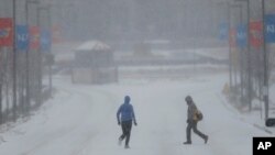 A jogger and pedestrian cross a snowy Jayhawk Boulevard on the University of Kansas campus in Lawrence, Kansas, Feb. 4, 2014.