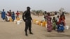 FILE - A Cameroonian police officer enforces order in Minawao, Cameroon, March 15, 2016.