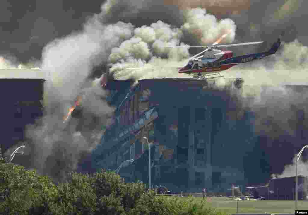 Poytaxt Vashington tashqarisida Pentagon binosiga kelib urilgan samolyot yetkazgan talofat qutqaruv vertolyotida baholanmoqda. Arlington, Virjiniya shtati. 2001-yil, 11-sentabr.