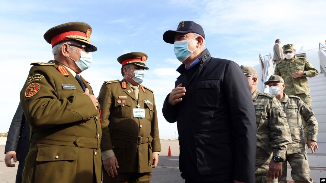 Turkey's Defense Minister Hulusi Akar, center, and other top Turkish military commanders, right, greet Libyan commanders, at airport, in Tripoli, Libya, Dec, 26, 2020.