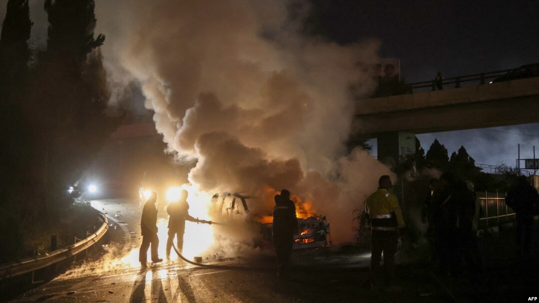 Firefighters extinguish a burning UNIFIL vehicle, set ablaze by protesters, on the road leading to Beirut's international airport on Feb. 14, 2025. 