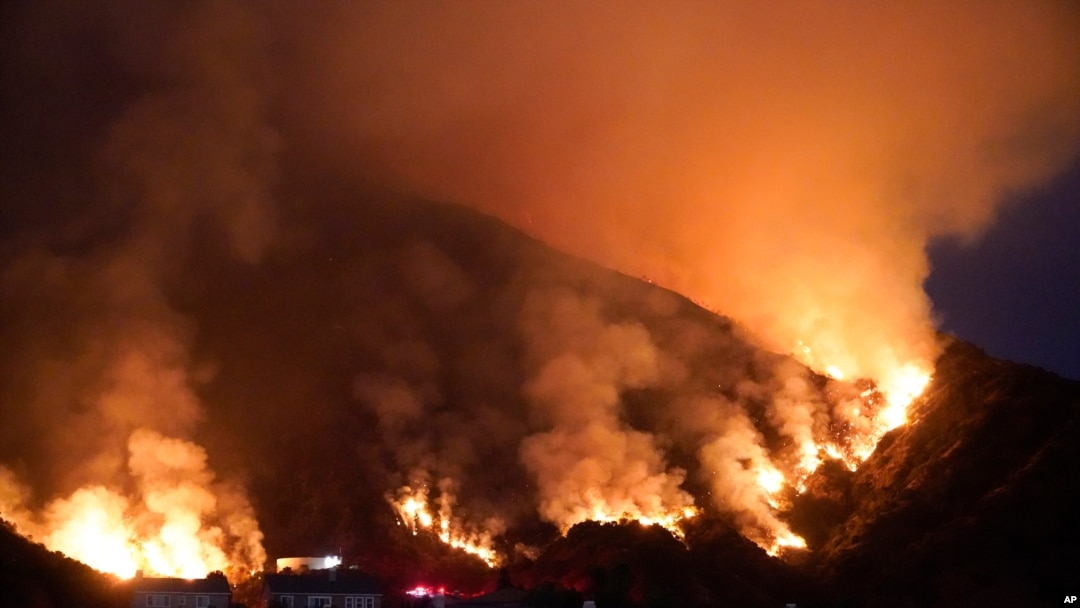 The Ranch Fire burns over a residential area, Aug. 13, 2020, in Azusa, California. Heat wave conditions were making difficult work for fire crews battling brush fires and wildfires across Southern California.