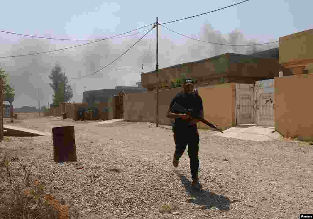 A fighter of the Asaib Ahl al-Haq Shi'ite militia takes cover from sniper fire, Sulaiman Bek, Sept. 1, 2014.